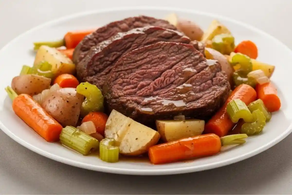 A tender, slow-cooked beef pot roast served with carrots, potatoes, and onions, simmered in savory broth to create a rich and flavorful meal